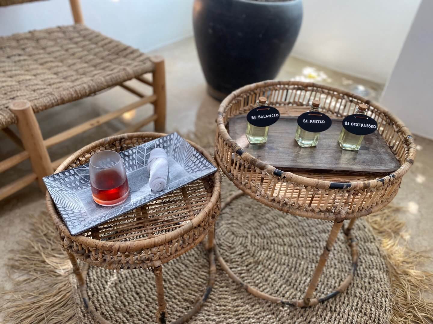 Wicker tables with 3 massage oils in glass bottles on one and a hot towel and Rooibos tea on the other