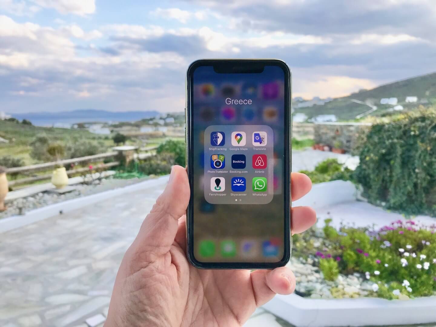 Hand holding a phone with a folder of apps called Greece