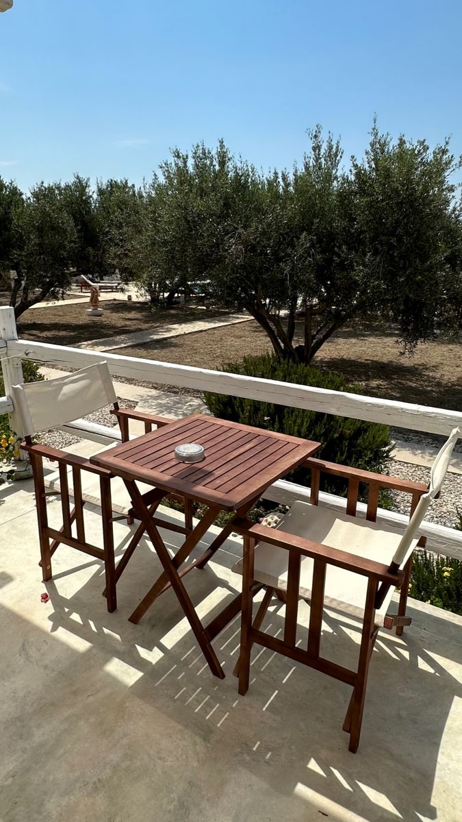 One of the best places to stay in Milos is Fantasy Rooms. This is a room terrace with table and chairs looking onto the olive grove