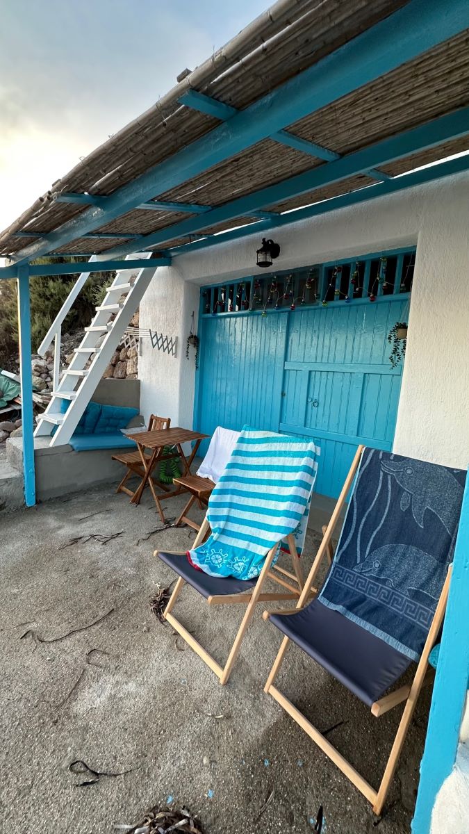 Converted fisherman's dwelling with turquoise wooden doors and deckchairs outside