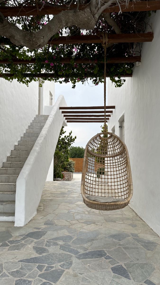 Whitewashed Cycladic cubed building with staircase and handing wicker seat