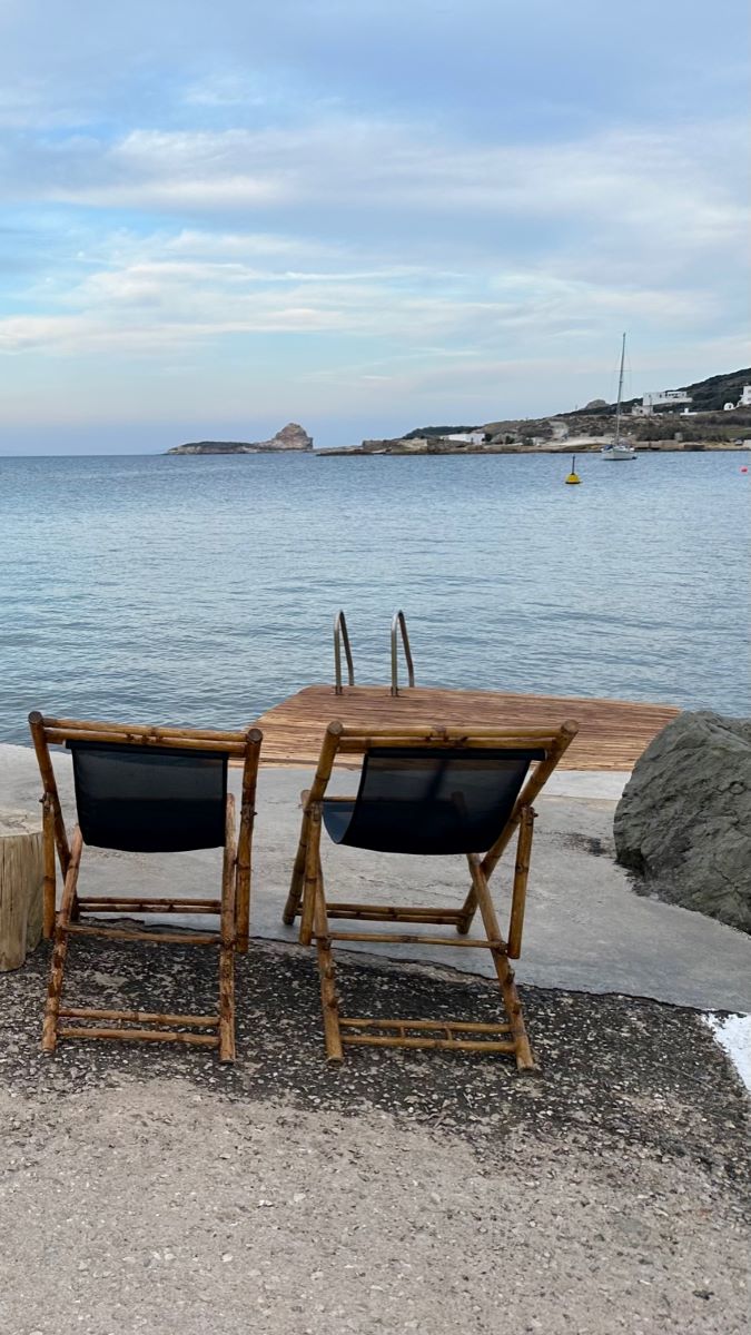 Contemporary wooden deckchairs in font of a private jetty into the sea