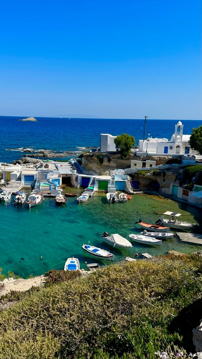 Small fishing boats in a bay at Mandraki with small buildings to house the boats